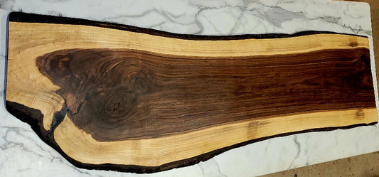 A .long live edge black walnut grazing board with a twist at the end and beautiful natural patterns