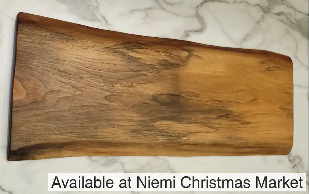 A live edge black walnut grazing board with basically a light background and attractive grain formations through the surface of the board