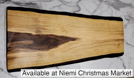 A Black walnut Grazing board with a light colour, some dark colouring at one end, and black bark on exterior