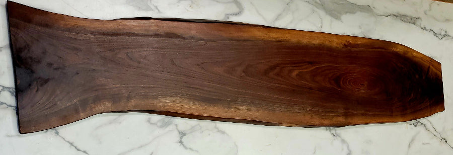 An hour glass shaped live edge black Walnut grazing board, with an irregular shape, dark colouring, and interesting wood patterns.