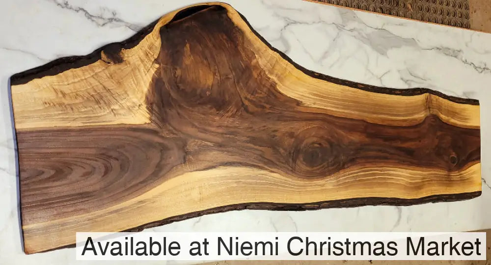 A large black walnut live edge grazing board with exciting patterns in its dark interior, surrounded by light colouring wood and black bark.